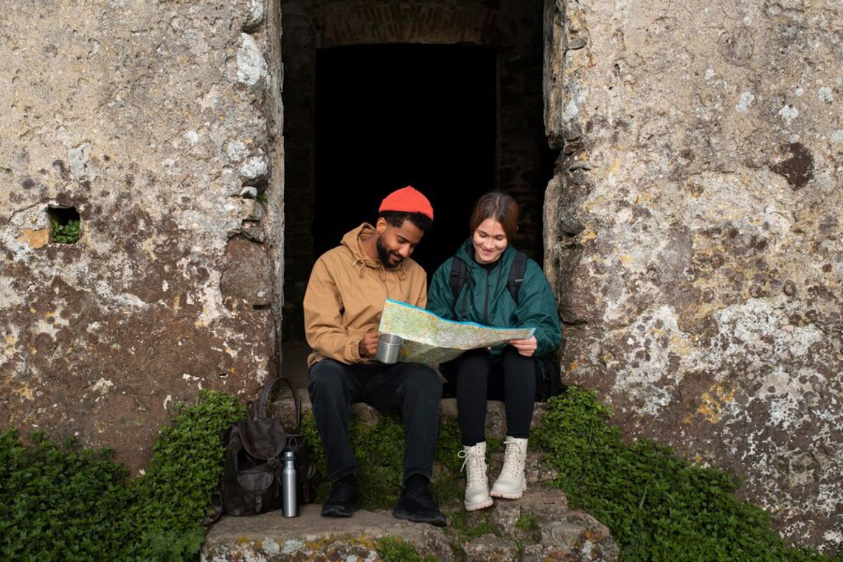 Two people sitting in a stone structure doorway, looking at a map together.