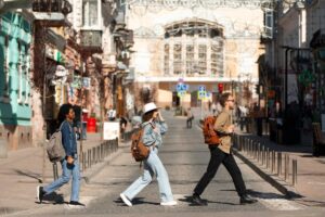 Three people crossing a sunlit urban street, emulating the iconic Beatles' Abbey Road album cover.